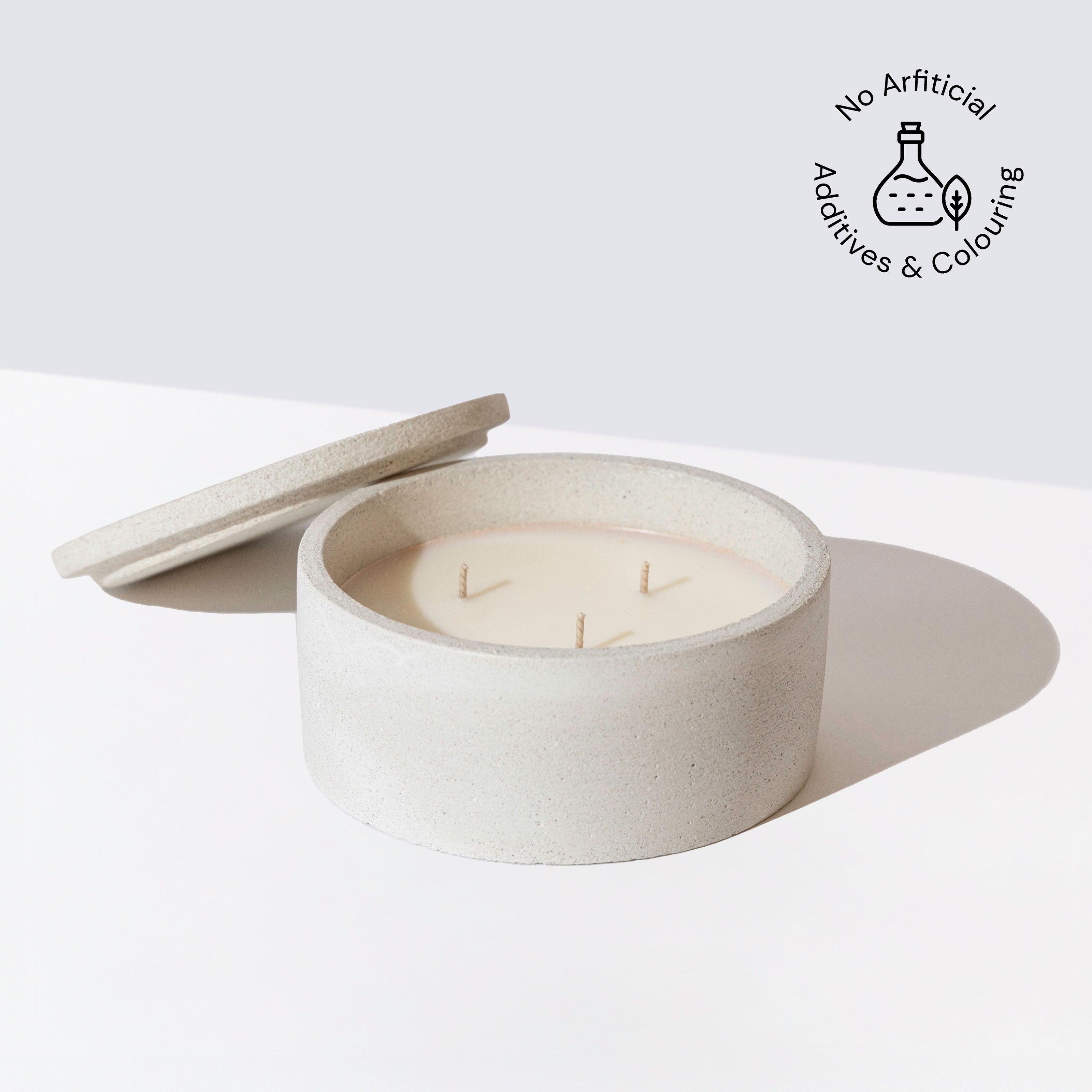 Eraya Aesthetic Round stone-patterned Soy wax candle in a matching container with a lid on a white background, featuring an icon indicating no artificial additives and coloring.