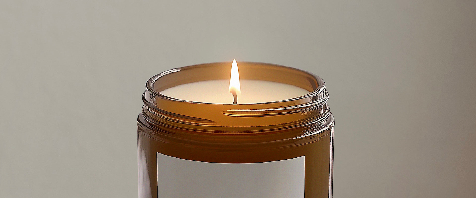 Candle in a glass jar with a brown lid on a plain background