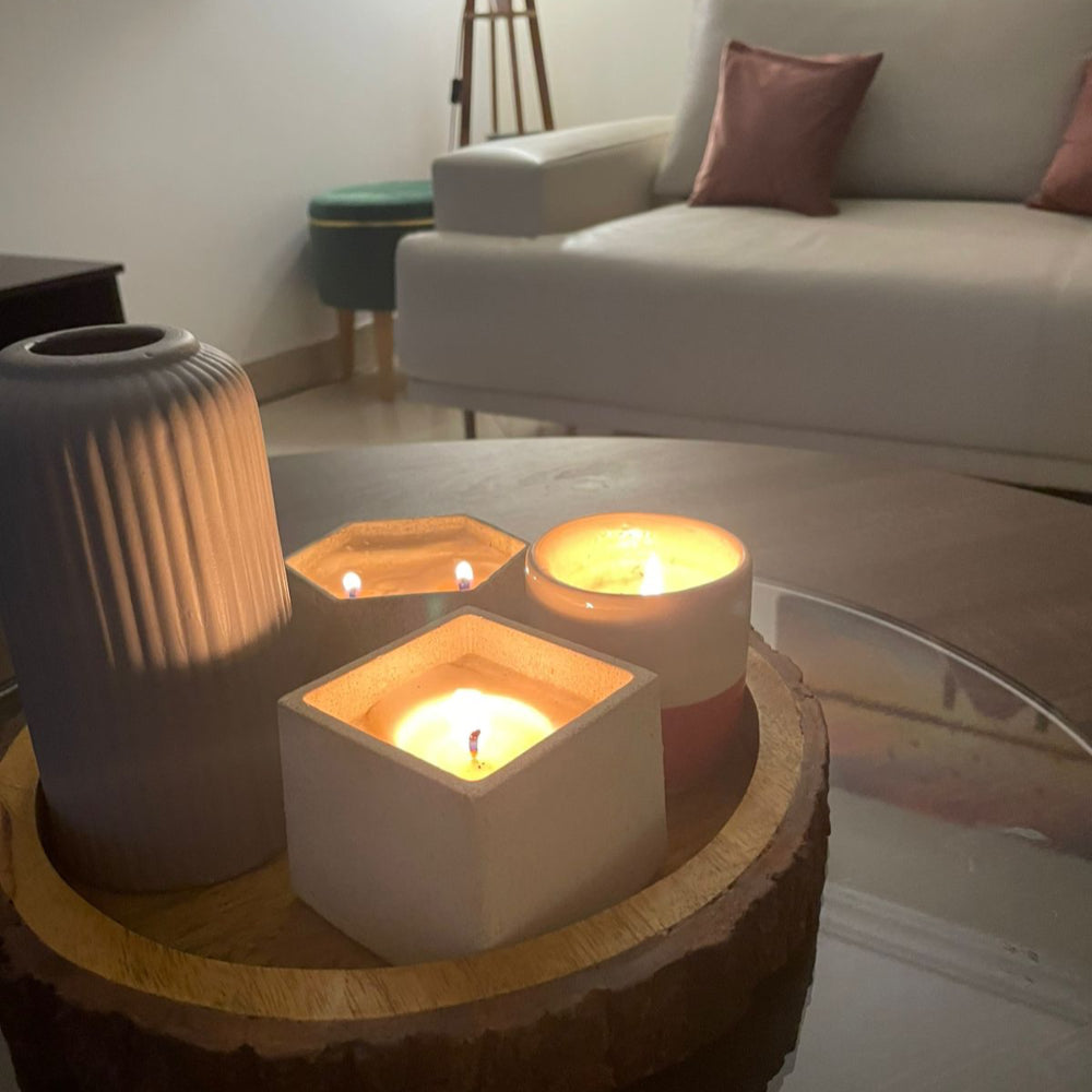Decorative candles on a wooden table with a vase in a living room setting.